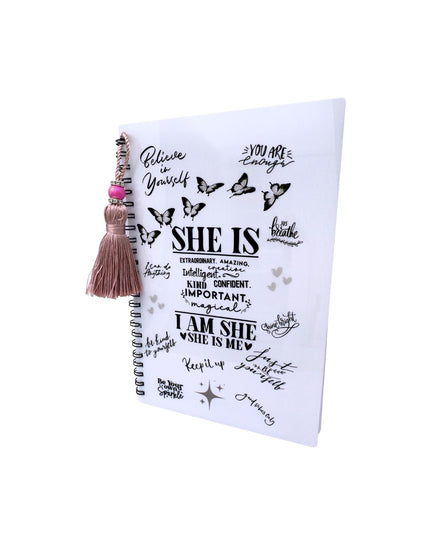 Notebook with motivational quotes and a tassel on a white background