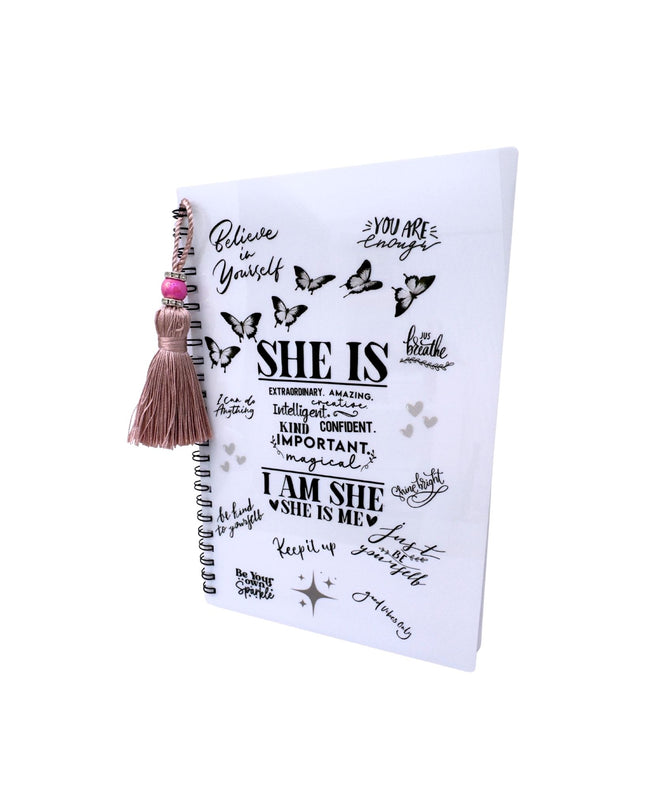 Notebook with motivational quotes and a tassel on a white background