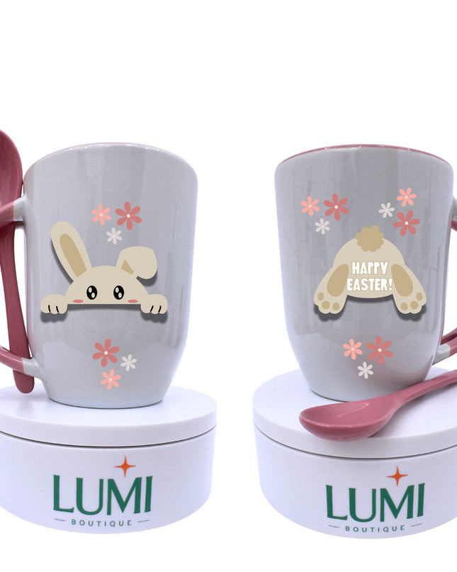 Two mugs with cartoon bunny designs and pink spoons on white stands, branded 'LUMI Boutique'.