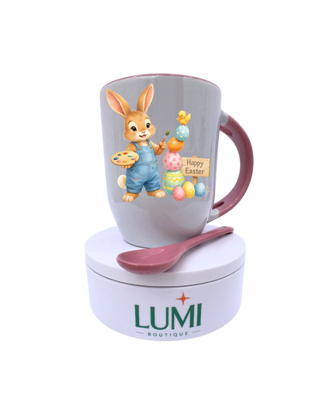 Easter-themed mug with a rabbit illustration, colorful eggs, and a spoon on a white background. LUMI Boutique branding visible.