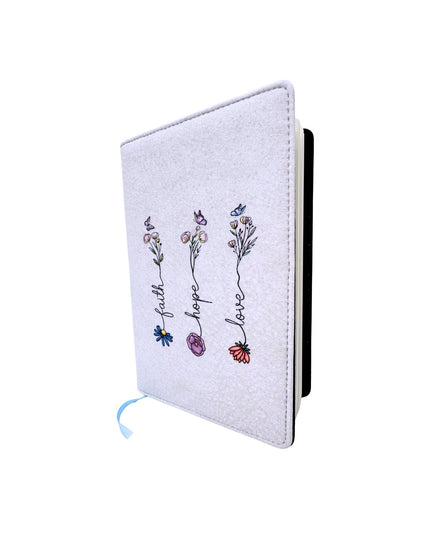 White notebook with floral designs and 'faith hope love' text on a white background