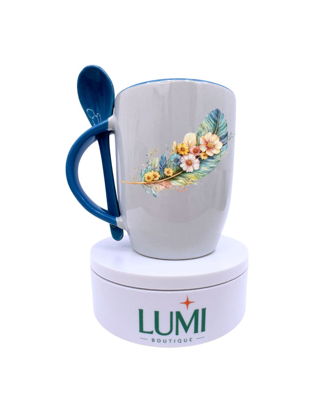 Mug with floral design and blue handle on a white stand with LUMI Boutique logo