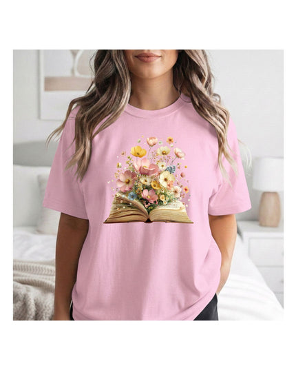 Person wearing a pink t-shirt with a floral book design in a bedroom setting