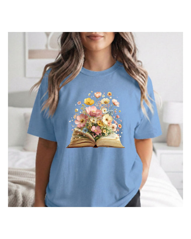 Person wearing a blue t-shirt with a floral book design in a bedroom setting