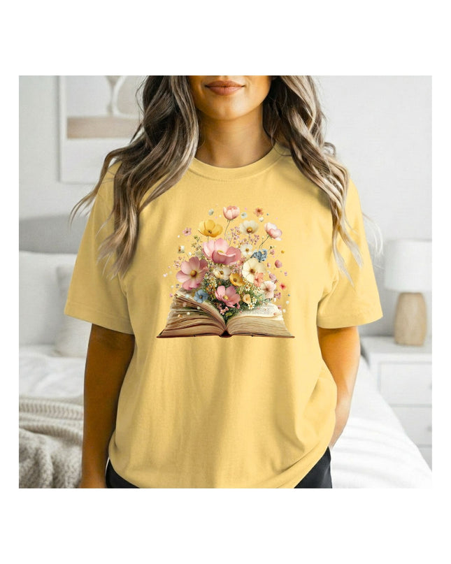 Person wearing a yellow t-shirt with a floral book design in a bedroom setting