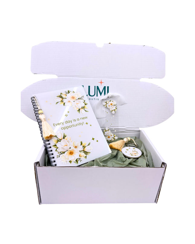 Gift box with a notebook, small plant, and decorative items on a white background
