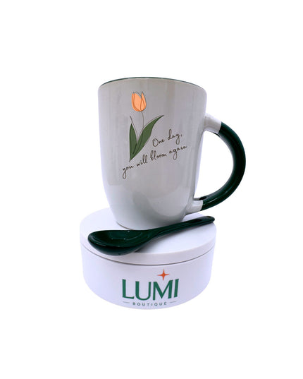 Mug with tulip design and message, accompanied by a spoon on a LUMI Boutique container.