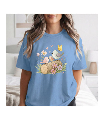 Woman wearing a blue t-shirt with a nature-themed design featuring birds and flowers.