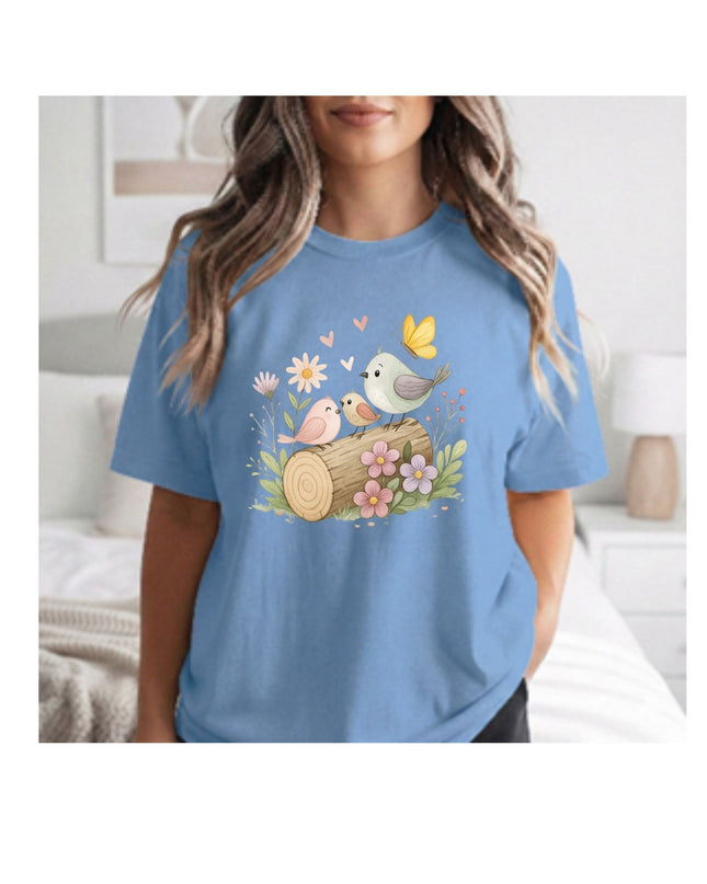Woman wearing a blue t-shirt with a nature-themed design featuring birds and flowers.