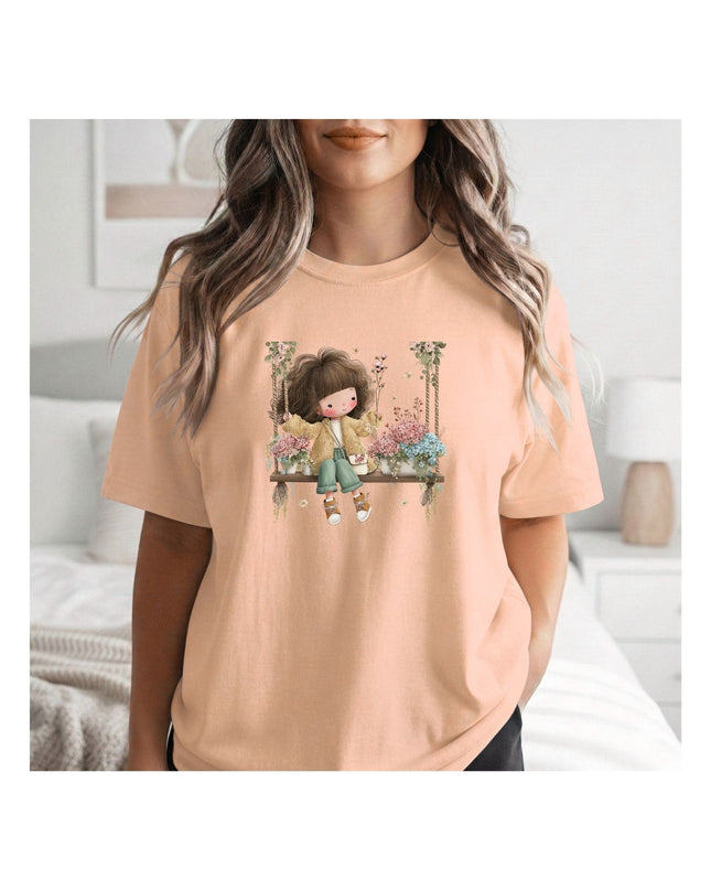  a beige t-shirt with a graphic design of a girl on a swing.