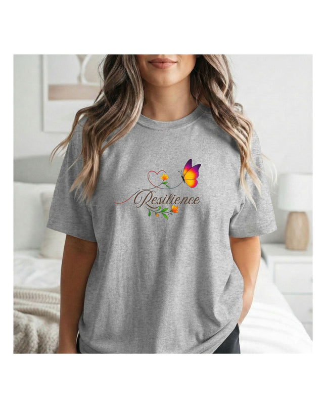 Person wearing a gray t-shirt with a colorful design and the word 'Resilience' on it, standing in a bedroom.