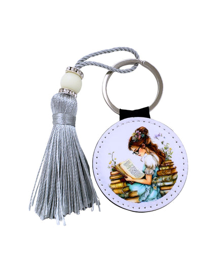 Keychain with tassel featuring an illustration of a woman reading a book.
