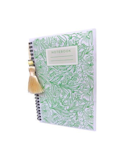 Notebook with green floral pattern and a decorative item on a white background