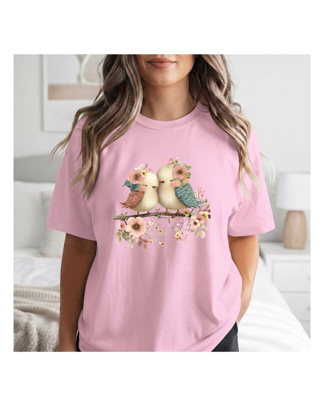 a pink t-shirt with a graphic of two birds on a branch.