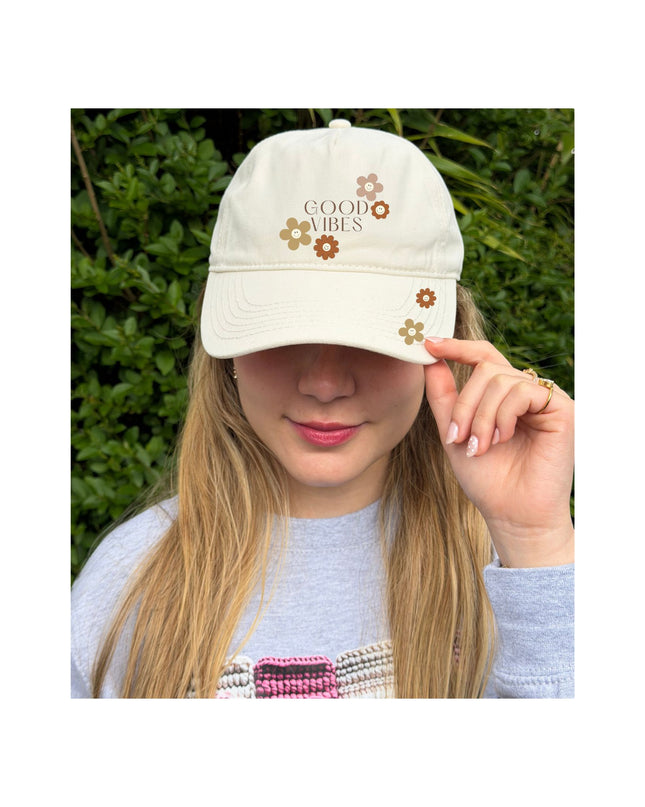 Person wearing a white cap with 'Be Kind' text, outdoors.