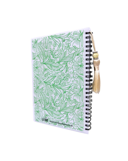 Notebook with green floral pattern and a brush on a white background