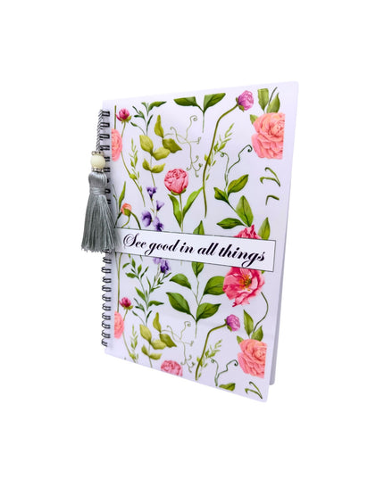 Notebook with floral design and tassel on a white background