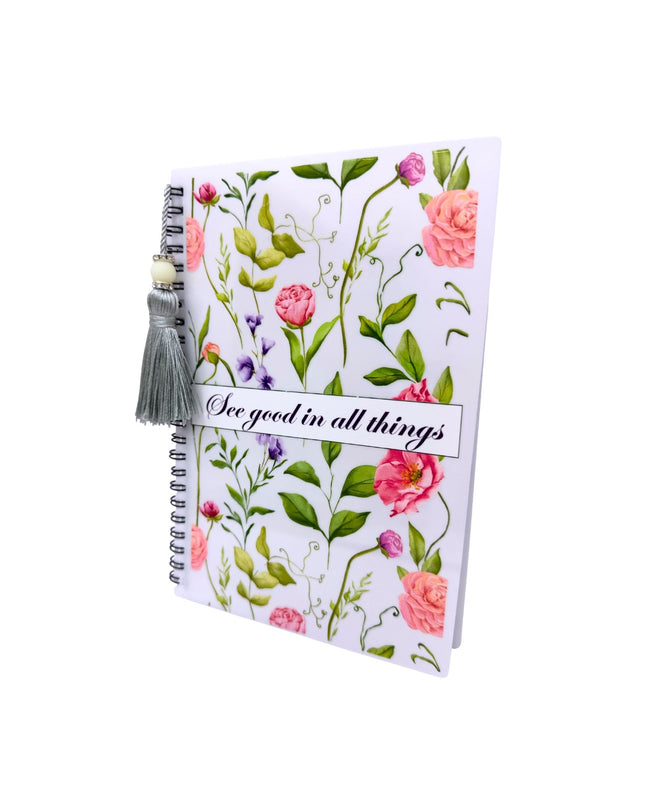 Notebook with floral design and tassel on a white background