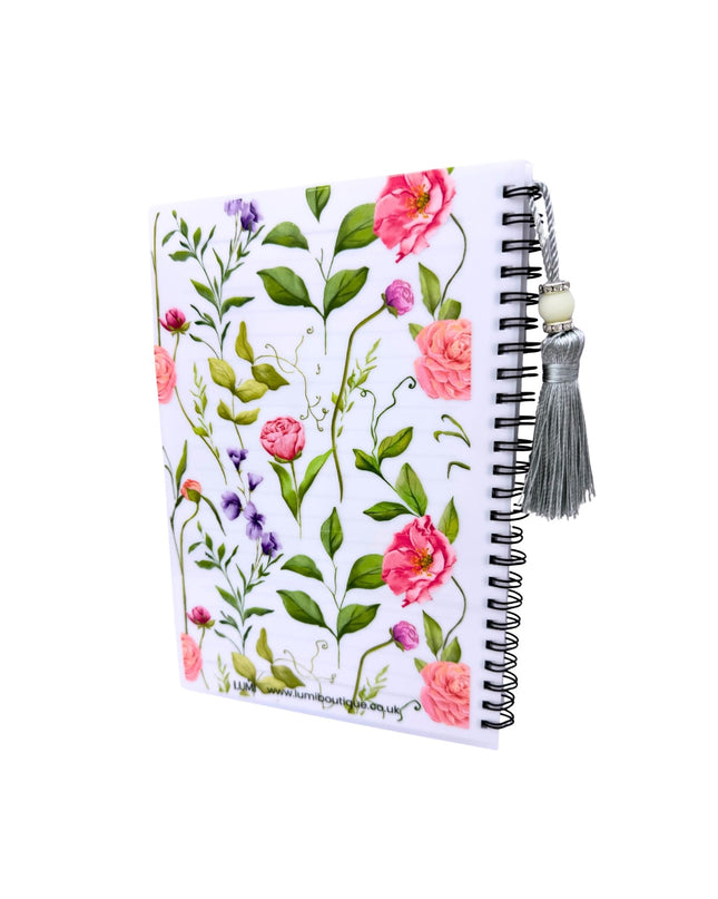 Notebook with floral design and tassel on a white background