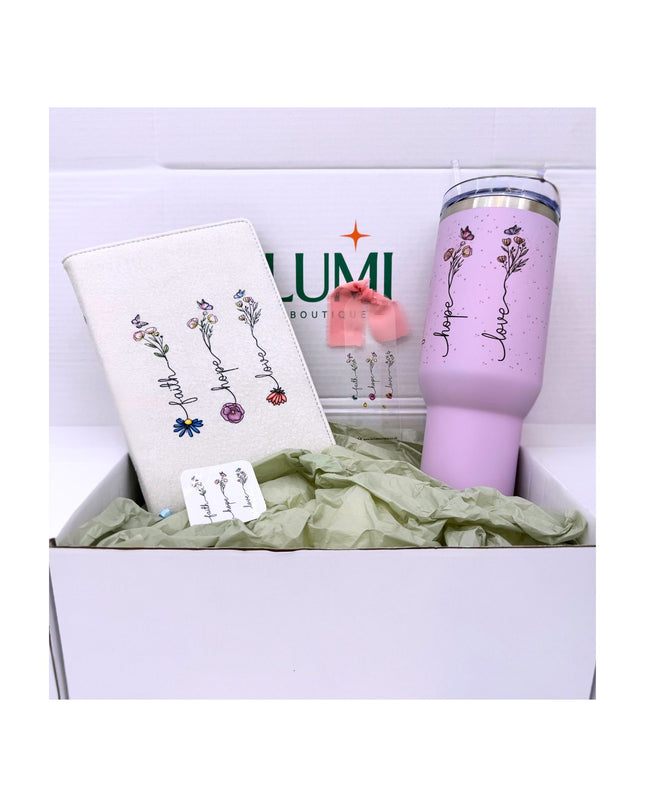 Pink tumbler with floral designs and text in a box with a white background