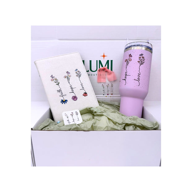 Pink tumbler with floral designs and text in a box with a white background