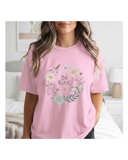 Person wearing a pink t-shirt with floral design and 'Be Kind' text in a bedroom setting