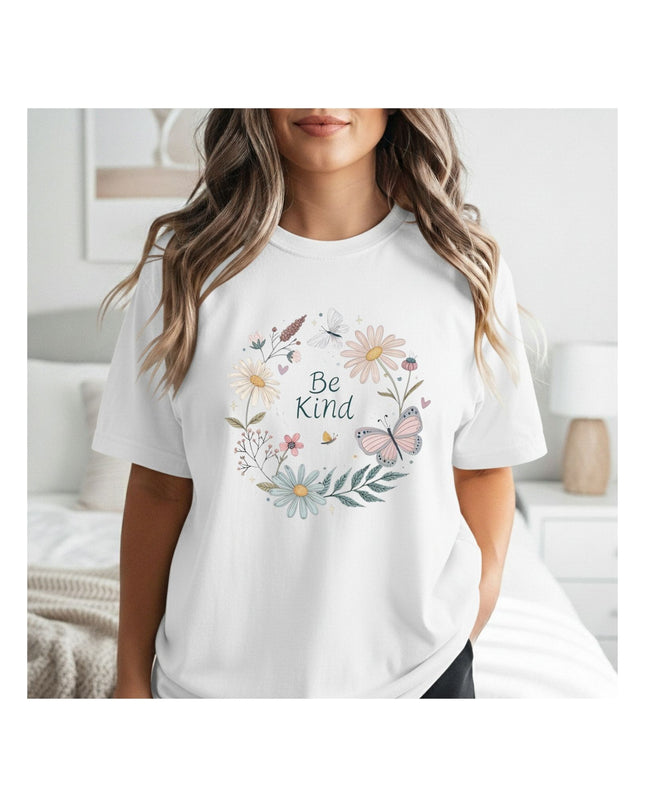 Person wearing a white t-shirt with floral design and 'Be Kind' text in a bedroom setting