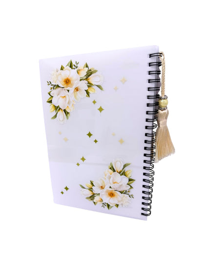 Notebook with floral design and tassel on a white background