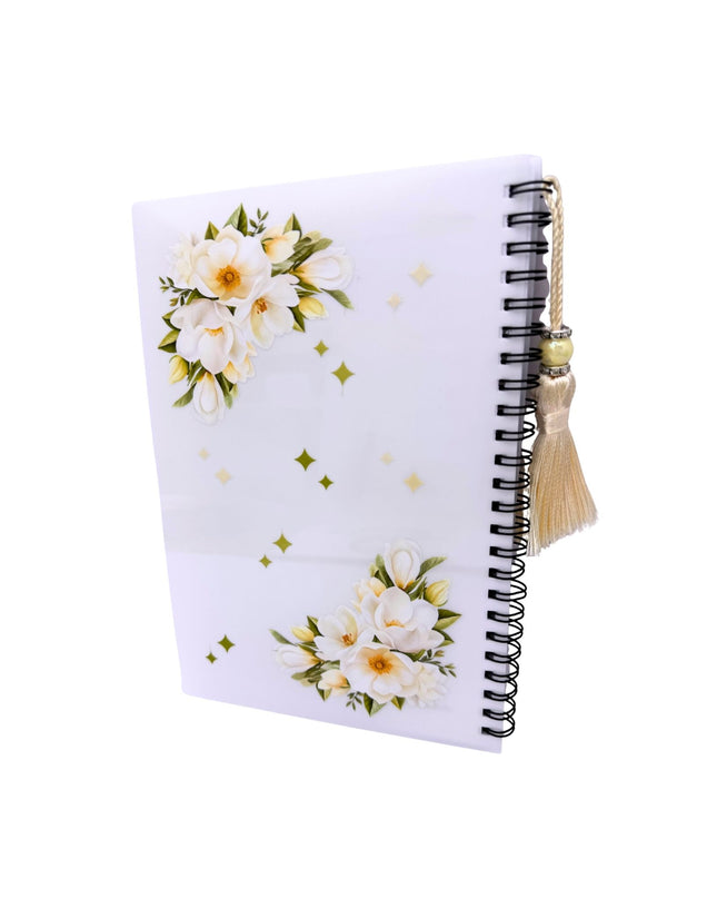Notebook with floral design and tassel on a white background